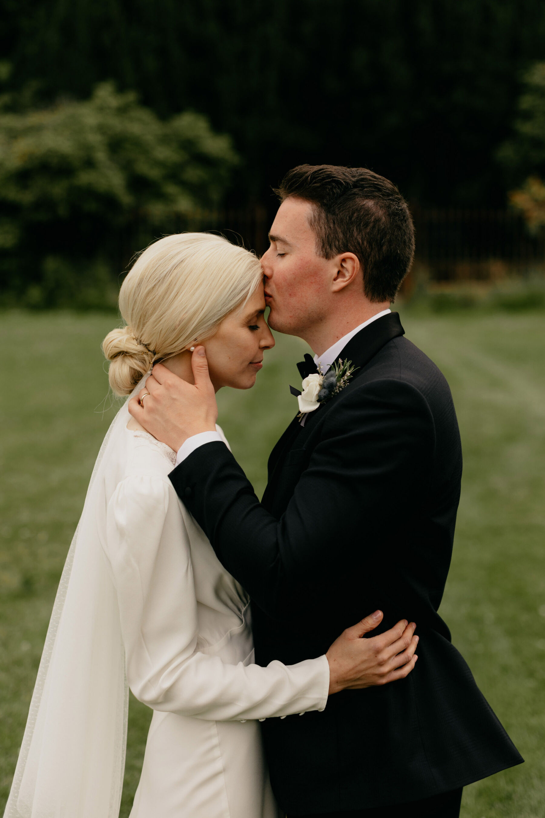 Groom in black tie kissing his bride in a Rixo Wedding Dress