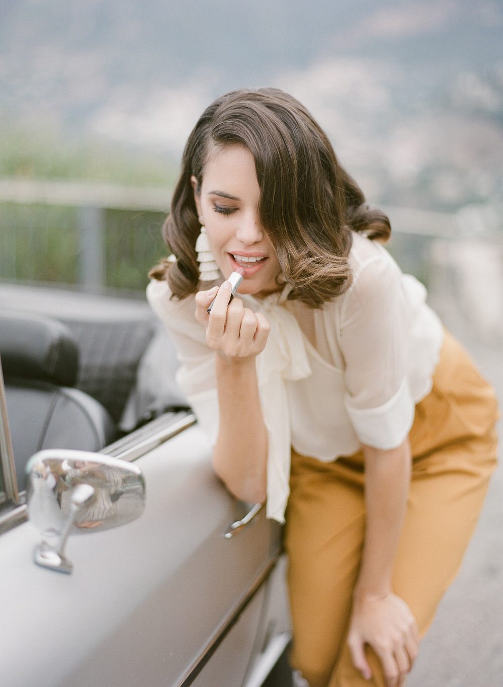 wife fixing her lipstick in the car mirror