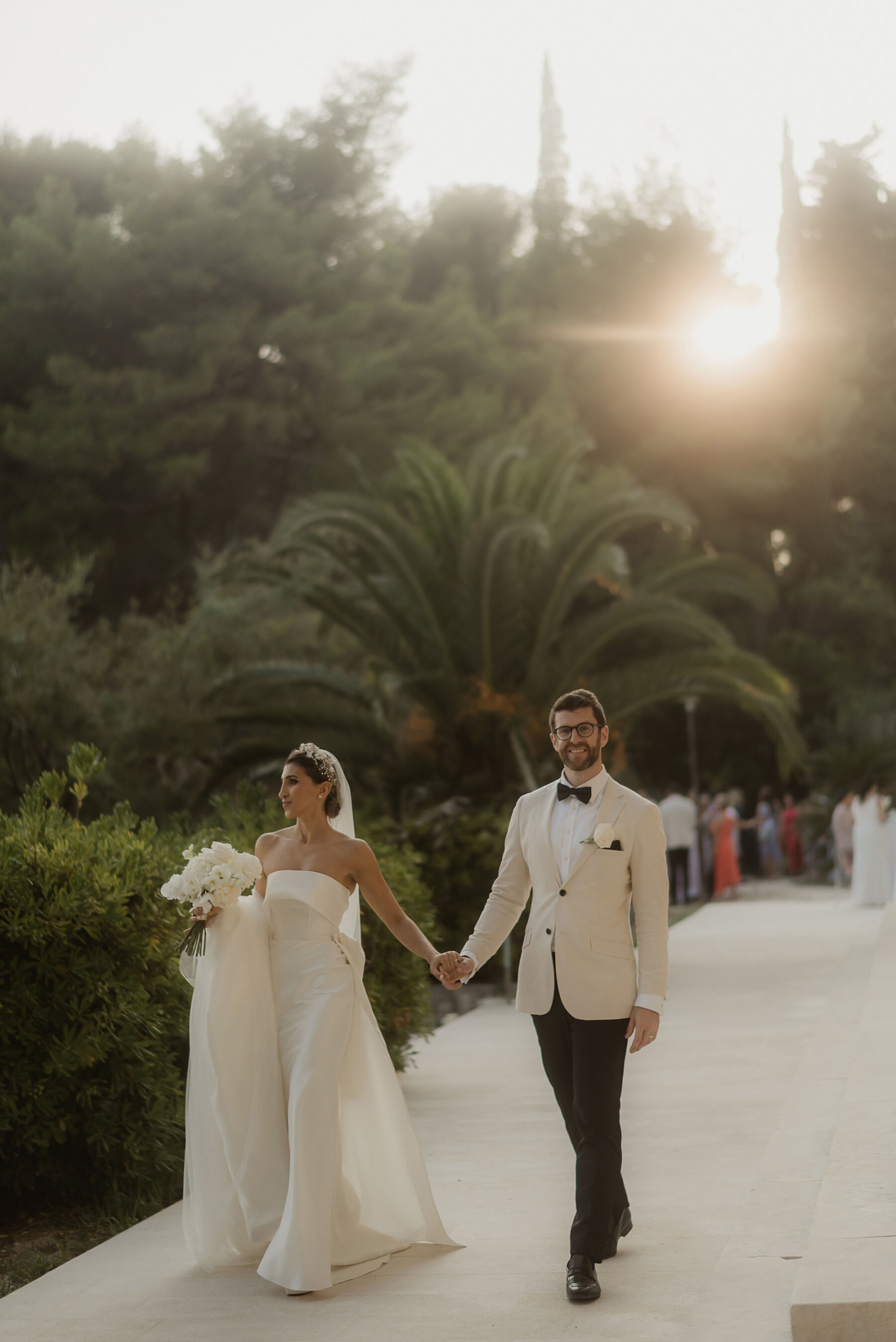 Sarah in Eva Lendel for her Classy & Contemporary Wedding in Croatia 38 Groom in white tux holding hands with bride in minimalist wedding dress by Eva Lendel