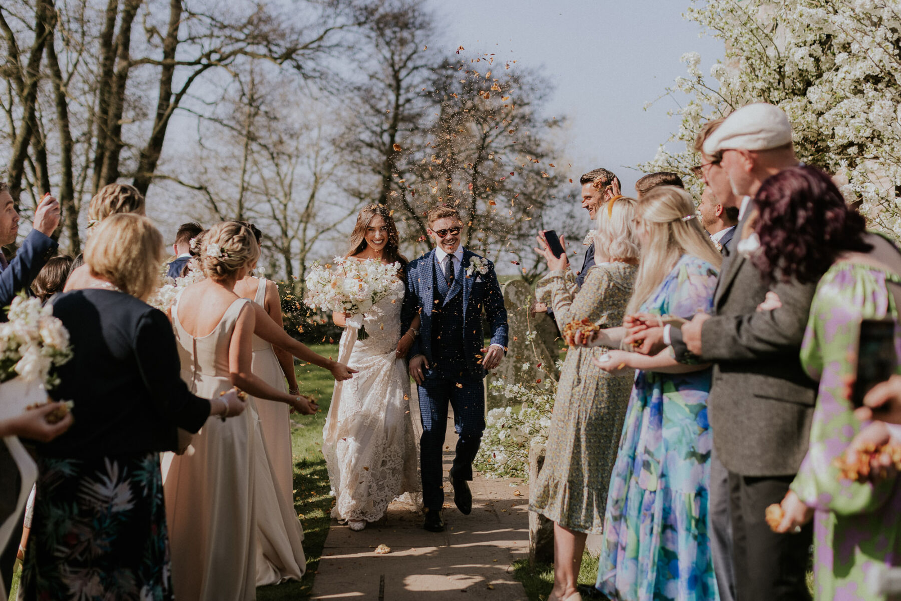Bride and groom smiling as they are showered with confetti at Dewsall Court, country house wedding venue in Herefordshire