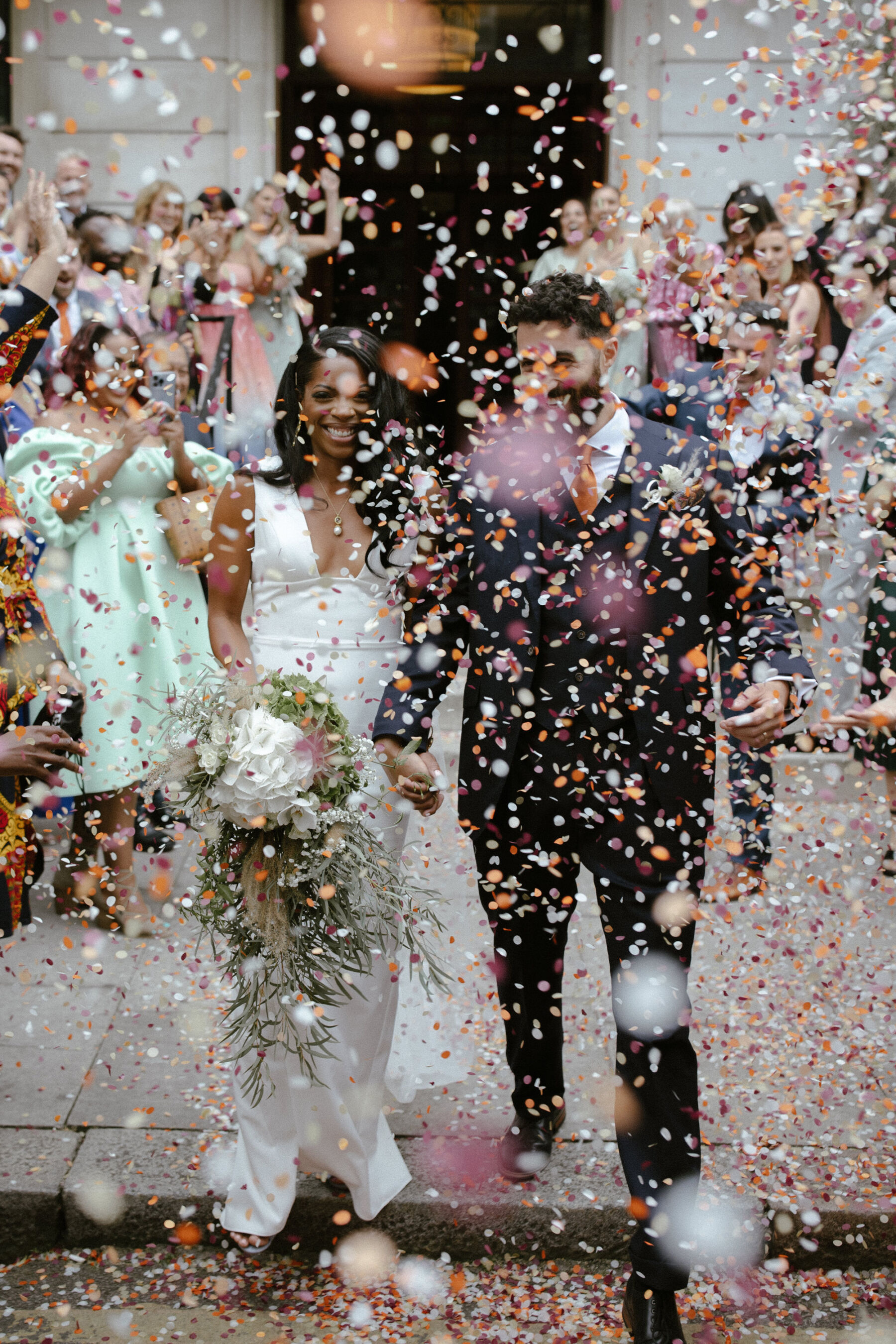 Kim in Sarah Seven, for her Modern, Minimalist & Chic City Wedding, Captured by Ruth Atkinson 18 Modern bride and groom shrouded in a cloud of colourful confetti. Bride wears a minimalist dress by Sarah Seven. Ruth Atkinson Photography.
