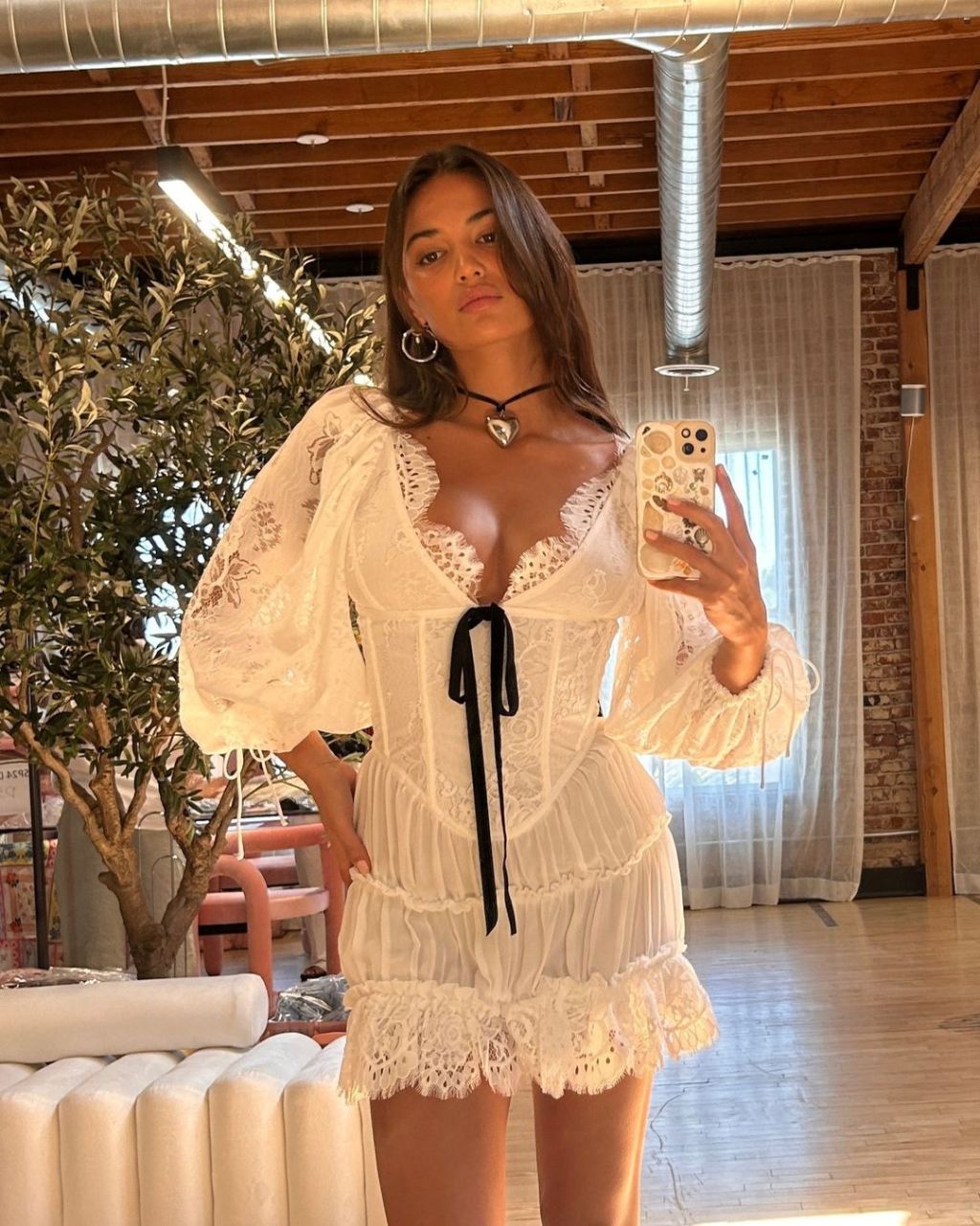 woman wearing a vintage style white lace mini dress coquette aesthetic outfit with a black bow detail on the neckline