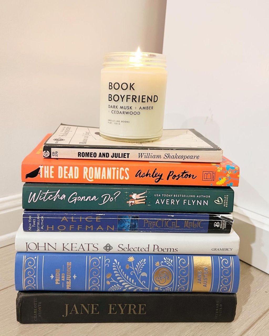 lit musky scented soy candle gifts for book lovers placed on a stack of novels