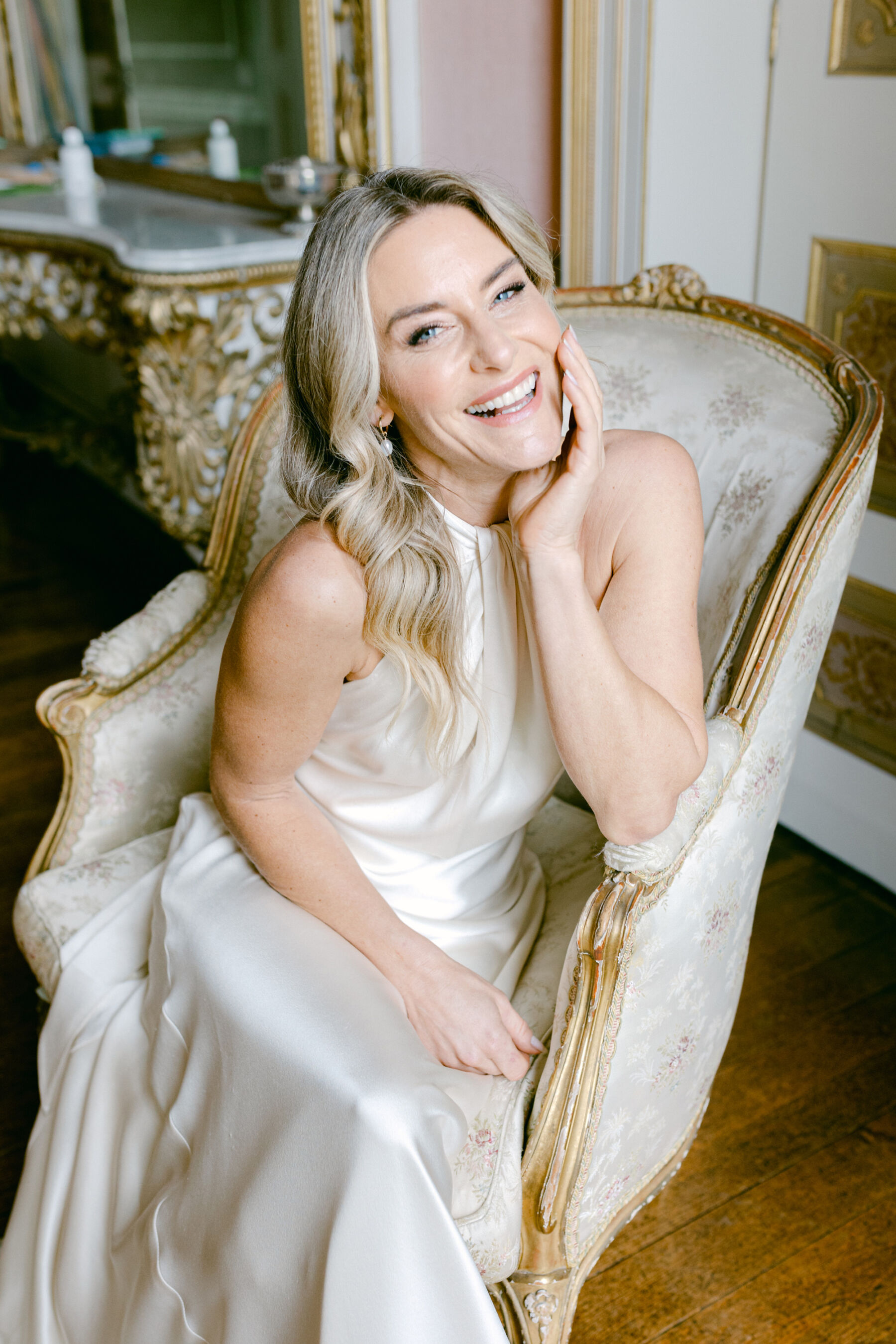 Pale Baby Blue Spring Wedding Inspiration at Avington Park, Featuring Halfpenny London 21 Laughing happy bride seated, wearing a silk halterneck wedding dress by Halfpenny London.