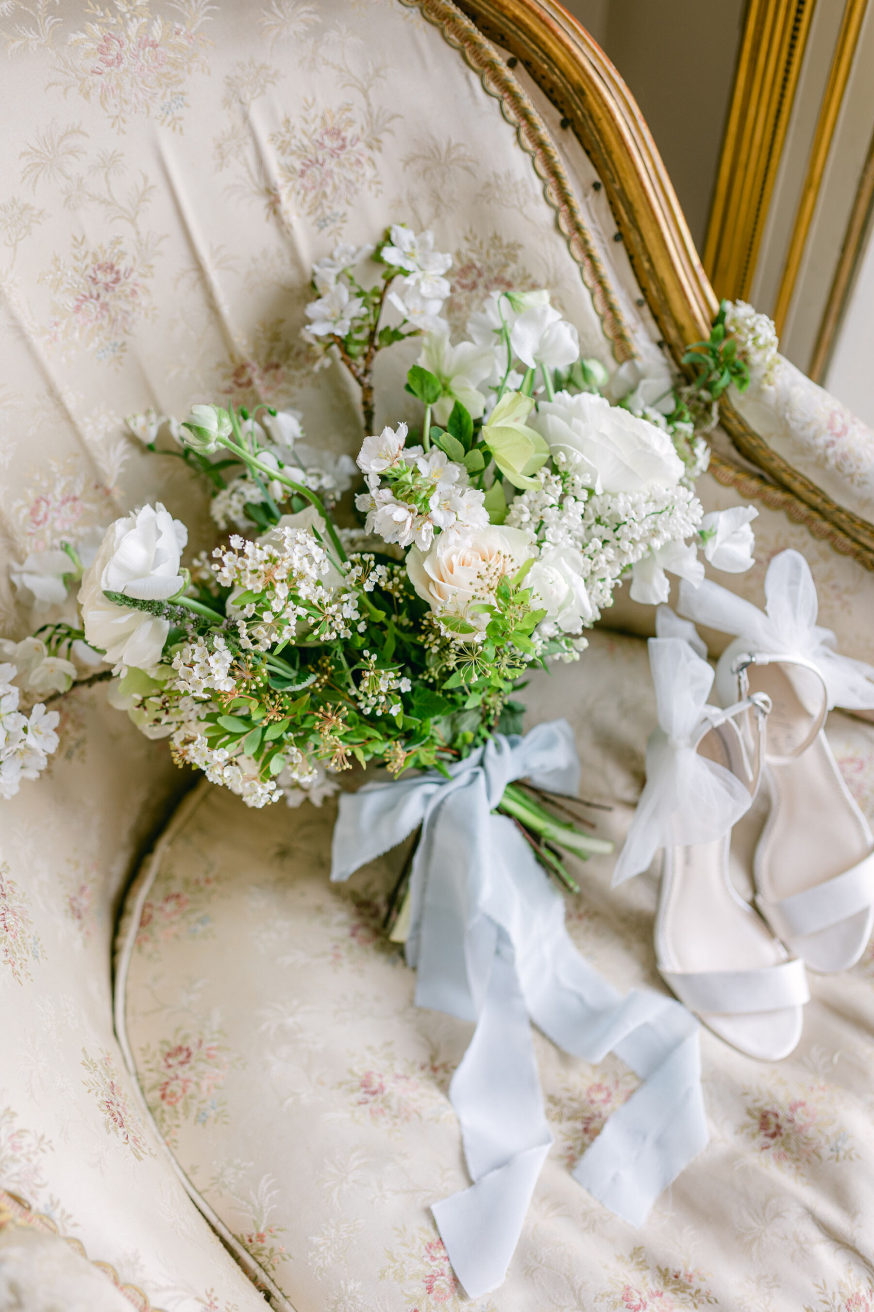 Pale Baby Blue Spring Wedding Inspiration at Avington Park, Featuring Halfpenny London 17 Elegant and romantic Spring bridal bouquet by Blue Sky Flowers. The bouquet is tied with a pale blue silk ribbon and comprises of all white flowers. Nearby is a pair of Bella Belle high heel open toe strappy bridal sandals, with a tulle ankle bow.
