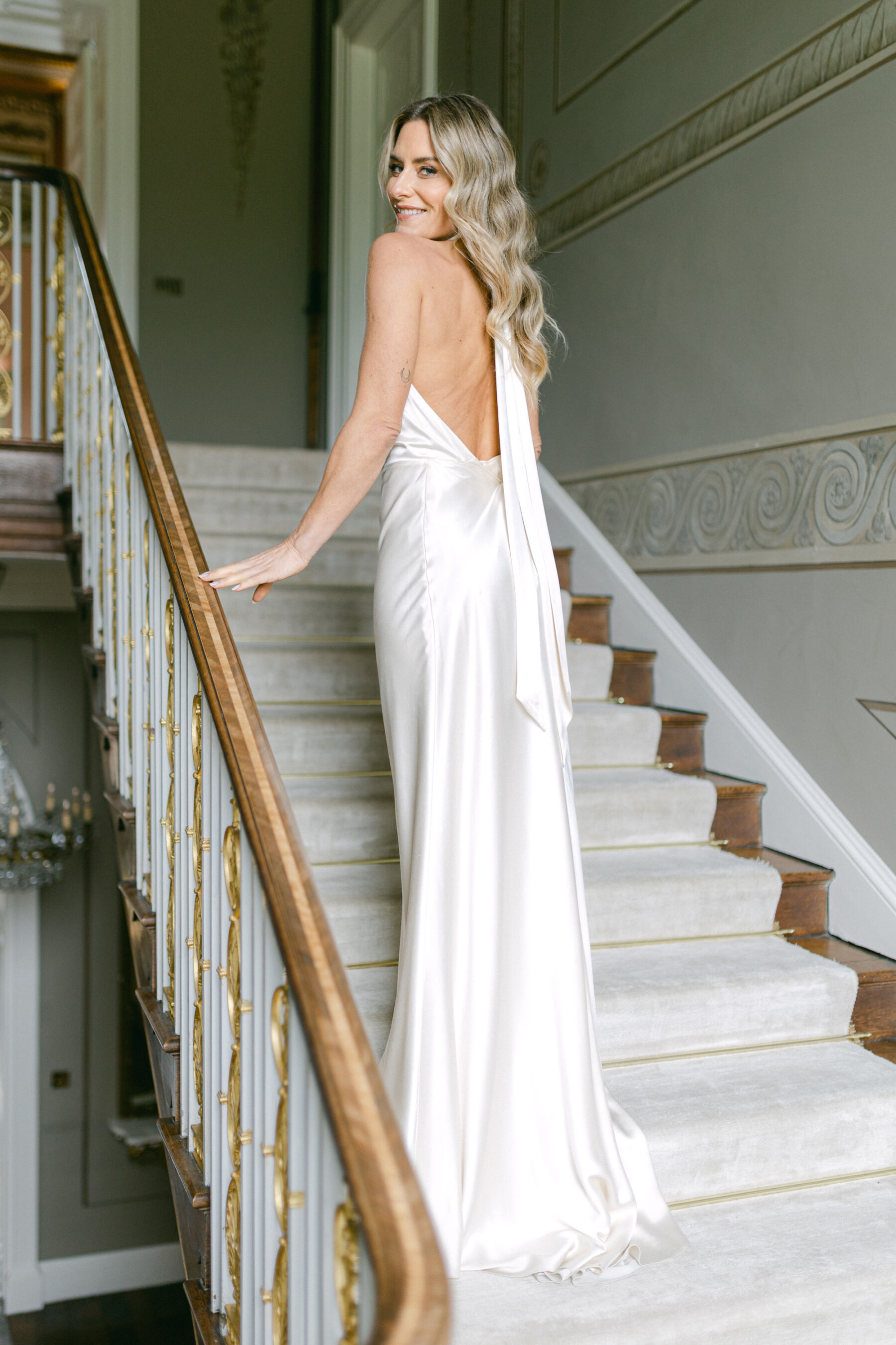 Pale Baby Blue Spring Wedding Inspiration at Avington Park, Featuring Halfpenny London 20 Halfpenny London silk halterneck. Bride standing on the stairs at Avington Park wedding venue, Hampshire.