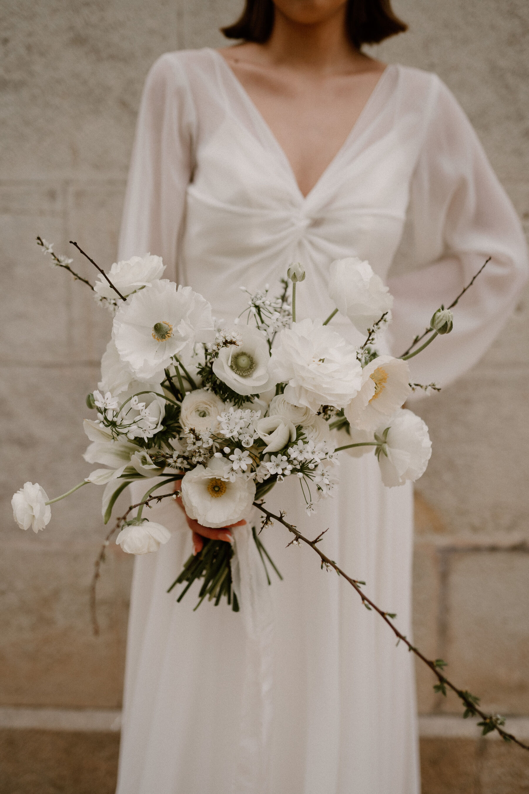 Elegant modern spring bouquet of seasonal white flowers and foraged twigs.