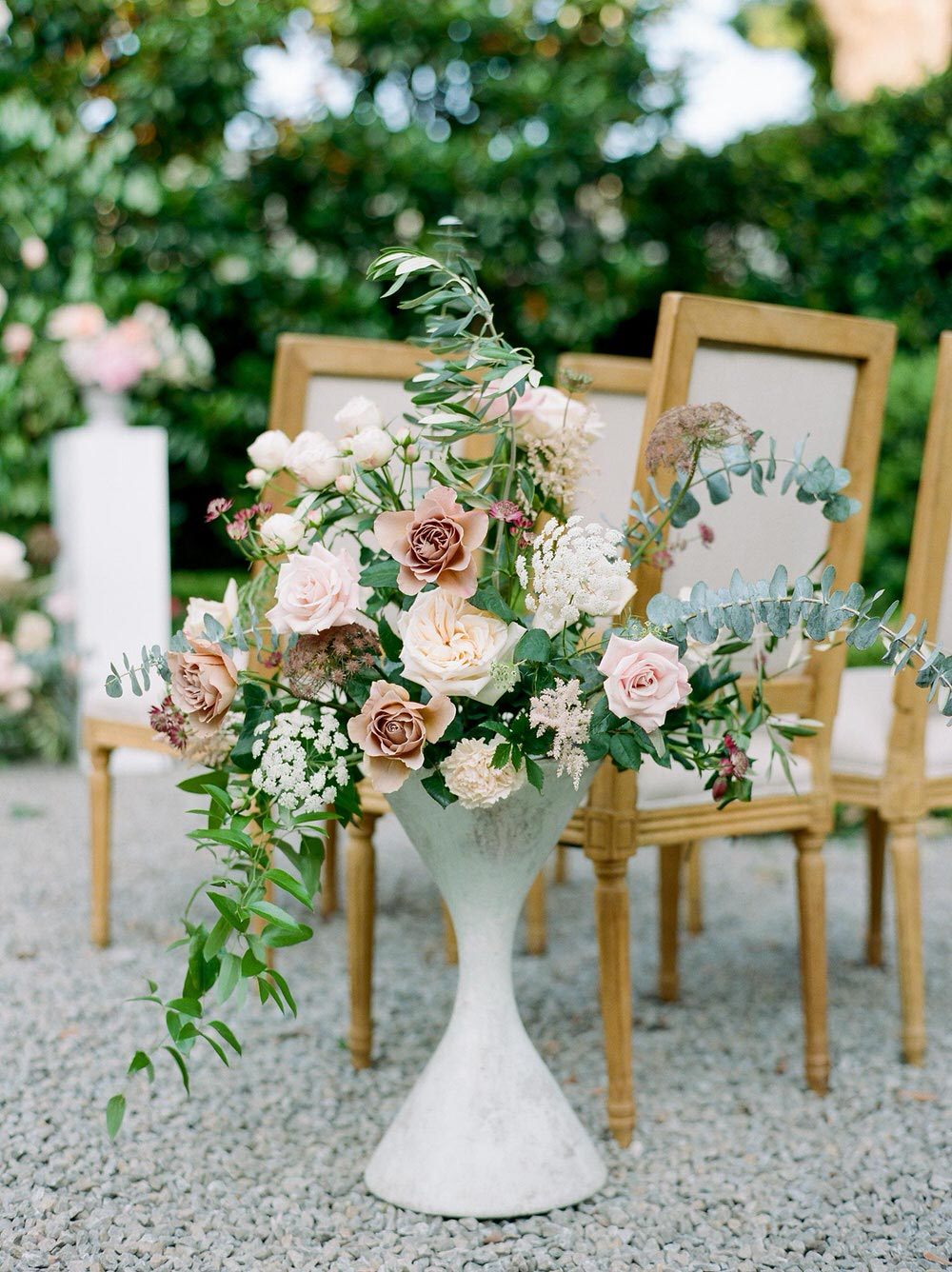 garden wedding ceremony floral arrangement with upholstered linen chairs