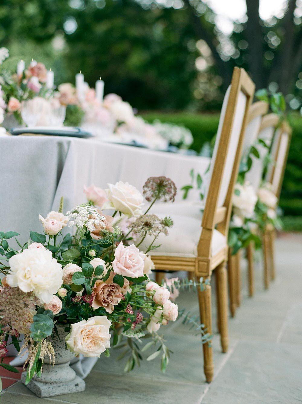 garden wedding tablescape with linen chairs and greenery chair swag