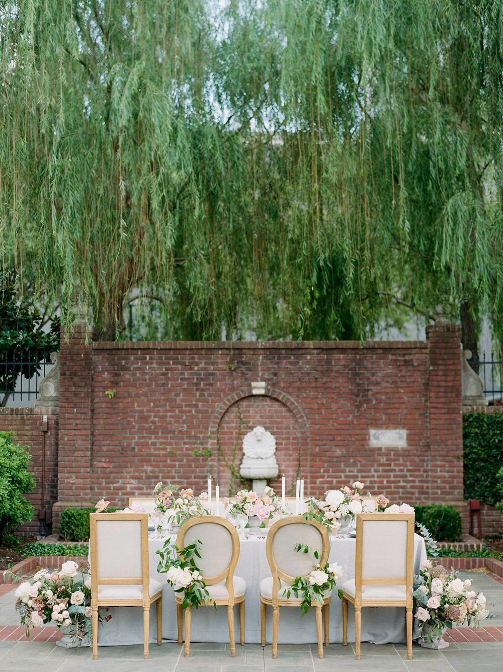 garden wedding tablescape with linen chairs and greenery swag