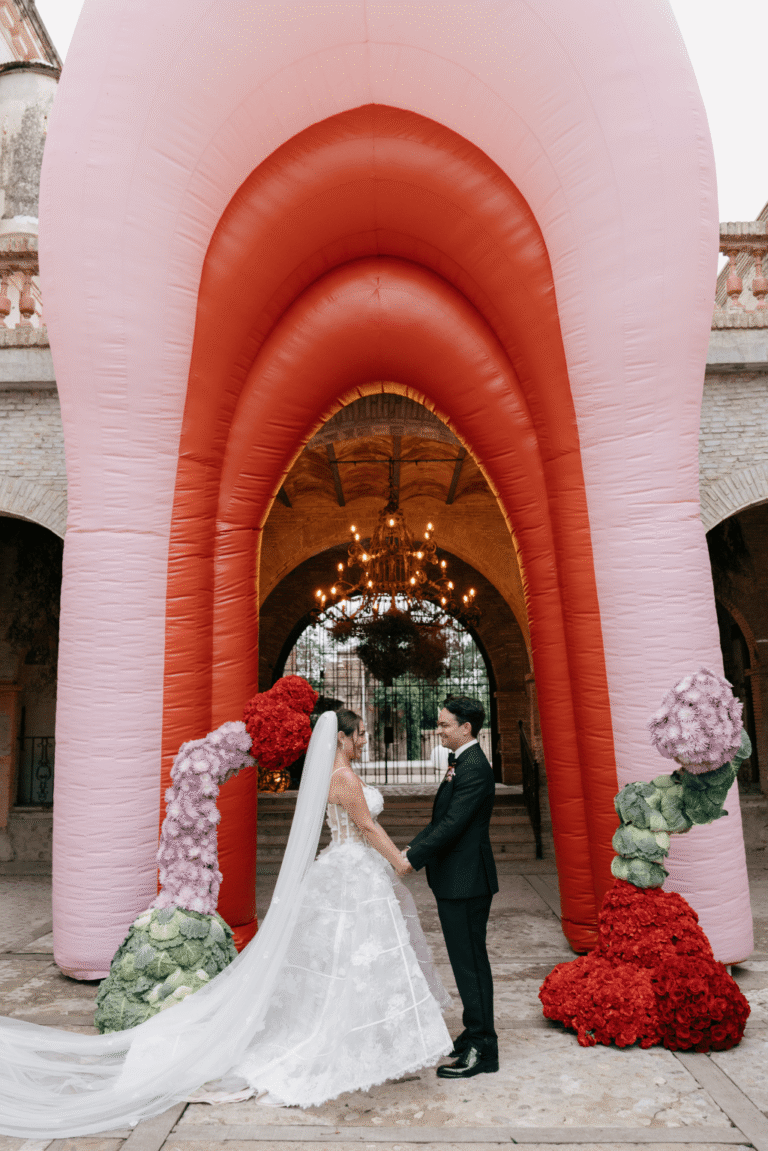 couple in front of giant inflatable pink and red wedding arch